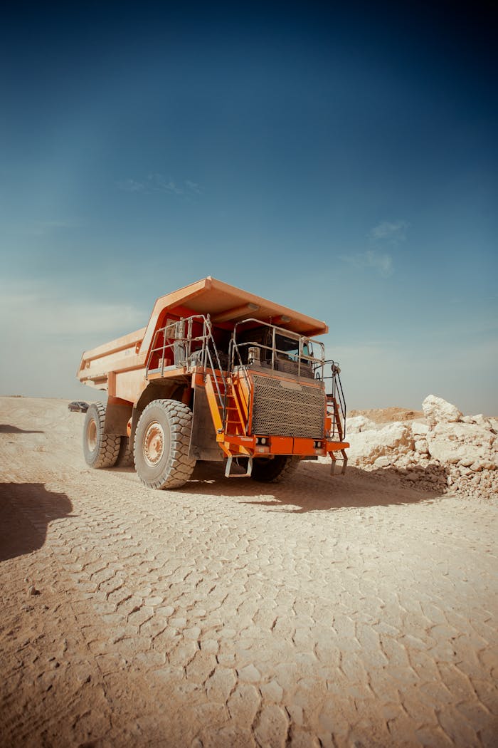 La résilience du secteur aurifère malien face aux défis Massive dump truck on a dusty road in Texas City desert, clear sky above.