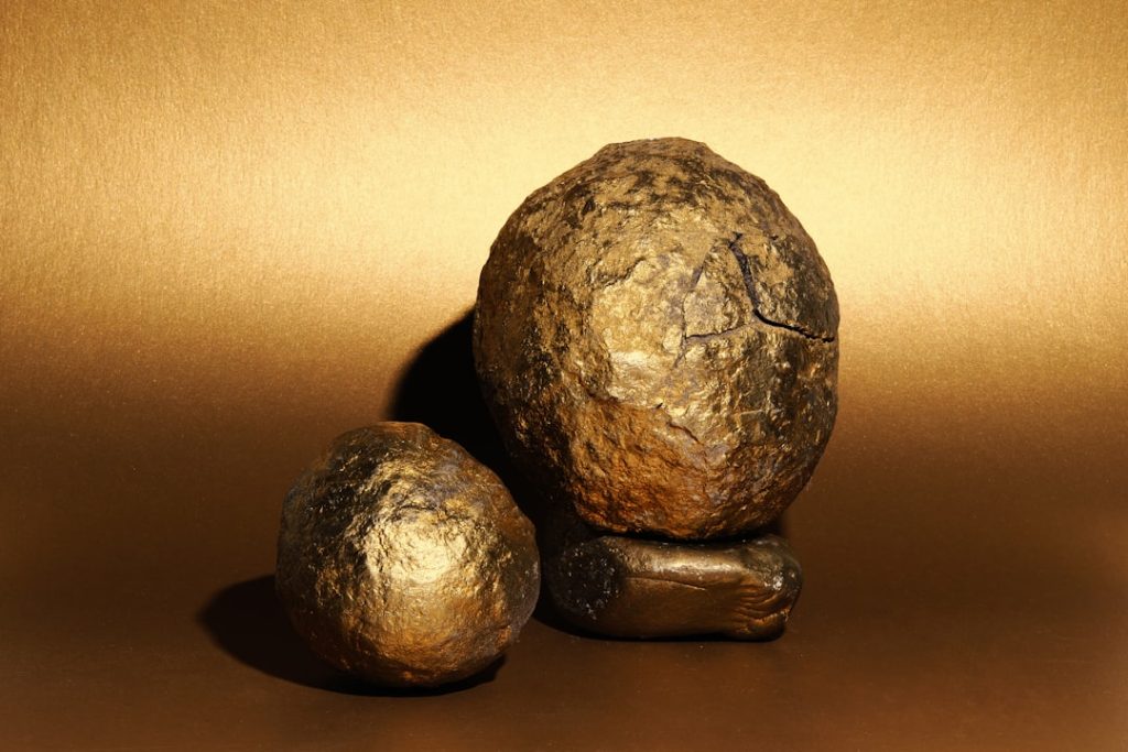 Very old cannonballs painted gold on a gold background.